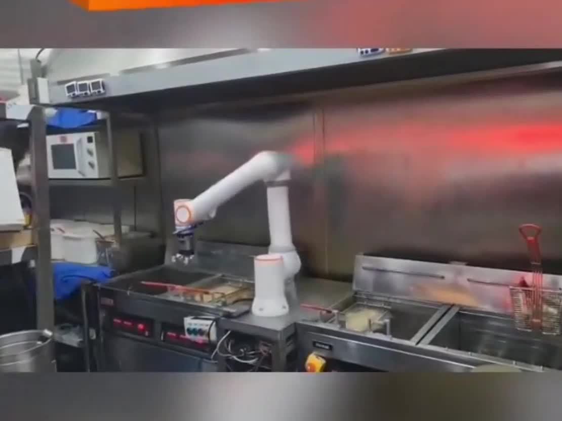ArmMate cobot holding a basket of product beside a fryer.